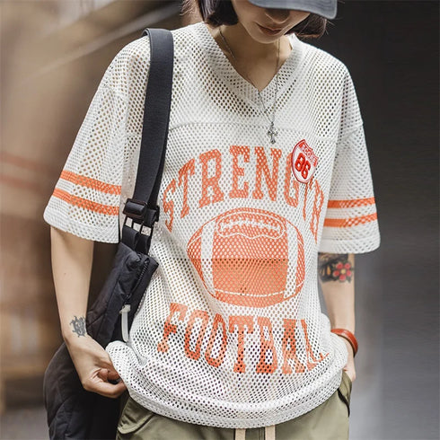 Person wearing a white mesh sports jersey with orange text and graphics, holding a black bag.